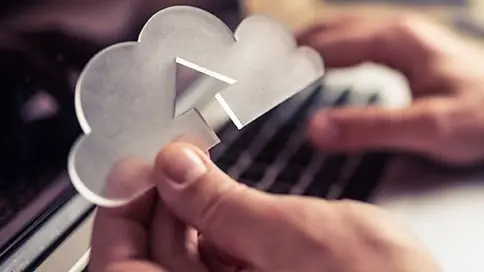 Symbol cloudu držený nad klávesnicí notebooku
